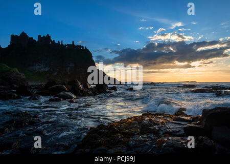 Ruins of Dunluce castle silhouetted by the sunsetting on the Irish coast Stock Photo