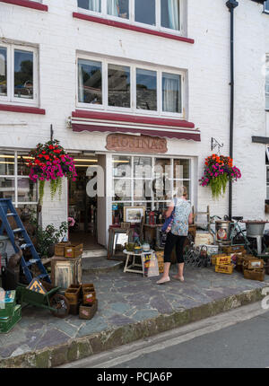 Woman looks at pavement display of goods outside Rosina's gift and vintage furniture shop in Polperro, Cornwall, England, UK Stock Photo
