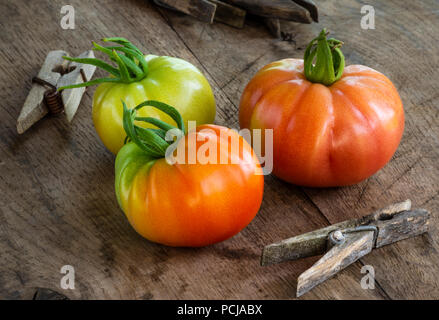 Three organic tomatoes on old wooden table Stock Photo