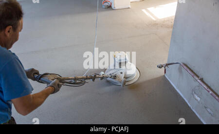Laborer performing and polishing sand and cement screed floor. Sand and cement floor screed. Stock Photo