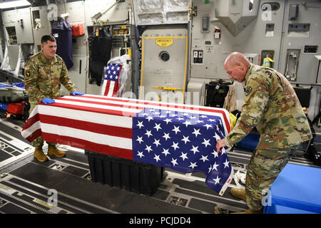 U.S. Army Staff Sgt. Marc Weyrick, left, and Sgt. 1st Class Eric Feltz, mortuary affairs specialists assigned to the Defense POW/MIA Accounting Agency (DPAA), secure a U.S. flag onto a transfer case aboard an Air Force C-17 Globemaster III enroute to Joint Base Pearl Harbor-Hickam, Hawaii, from Osan Air Base, Republic of Korea, Aug. 1, 2018. The cases contain possible remains of service members lost during the Korean War and were transefered to DPAA's forensic laboratory in Hawaii to begin the identification process in support of the agency's mission to provide the fullest possible accounting  Stock Photo