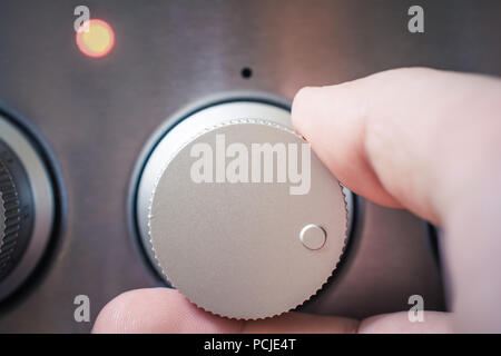 Front View Of A Male Hand Using Oven Controls, Oven And The Control Light Are On Stock Photo