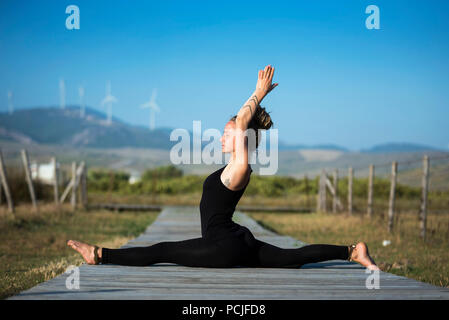 Woman on Los Lances beach doing front splits yoga pose, The Strait Natural Park, Tarifa, Cadiz, Andalusia, Spain Stock Photo