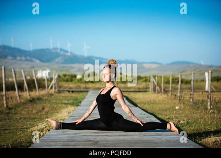 Woman on Los Lances beach doing front splits yoga pose, The Strait Natural Park, Tarifa, Cadiz, Andalusia, Spain Stock Photo