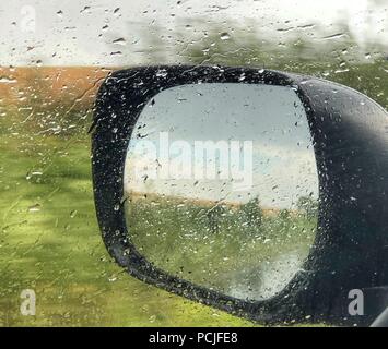Close-up of a wing mirror through a wet car window Stock Photo
