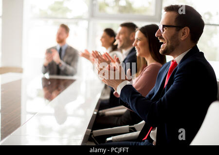 Businesspeople applauding while in a meeting at modern office Stock Photo