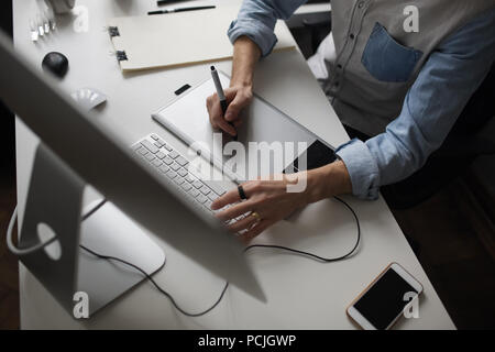 Young male designer using graphics tablet while working with com Stock Photo
