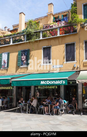 People eating at tables outside McDonald's restaurant, Cannaregio, Strada Nuova, Venice, Veneto, Italy in summer Stock Photo