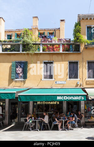 People eating at tables outside McDonald's restaurant, Cannaregio, Strada Nuova, Venice, Veneto, Italy in summer Stock Photo