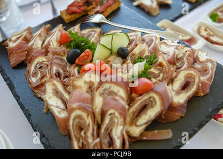 Meat rolls displayed on black plate with fork in background Stock Photo