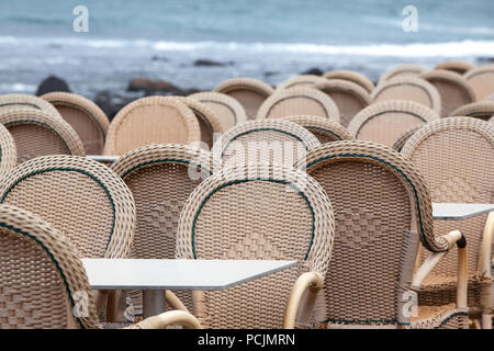 Caleta de Famara/SPAIN - Chairs and tables of an empty outdoor restaurant with the sea in the background, in Caleta de Famara, Lanzarote, Spain Stock Photo
