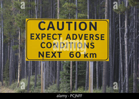 Caution sign on Spray Lakes Road warns about possible adverse conditions on back country roads in Alberta near Banff and Canmore. Stock Photo