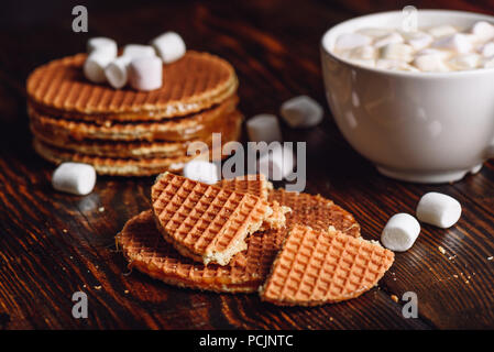 Stroopwafel with Broken One with White Cup of Cocoa with Marshmallow and Waffle Stack on Backdrop. Stock Photo