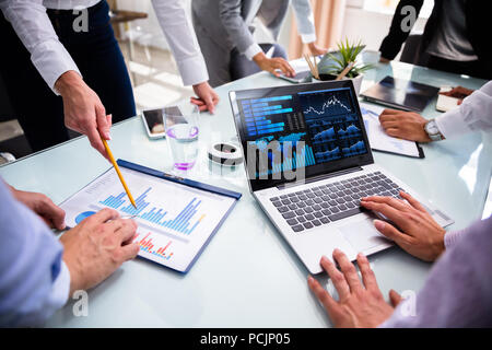 Businesspeople Using Laptop While Analyzing Graphs At Meeting Stock Photo