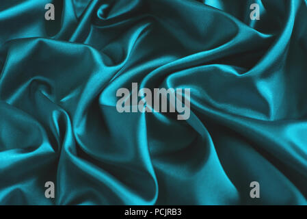 Close up of ripples in turquoise silk fabric. Satin textile background. Stock Photo