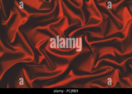 Close up of ripples in red silk fabric. Satin textile background. Stock Photo