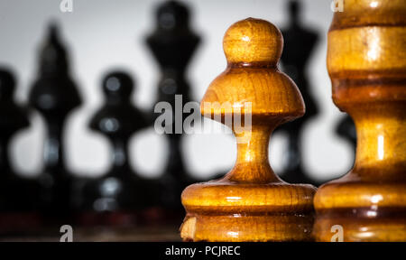 Wooden chess pieces stand on the board in the starting position before the battle. Stock Photo