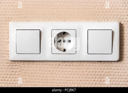 A block of light switches and a socket on a beige wall. Stock Photo