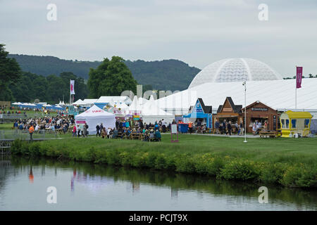 Large crowd of people at showground, many sitting by refreshment trade stands & marquee at busy RHS Chatsworth Flower Show, Derbyshire, England, UK. Stock Photo