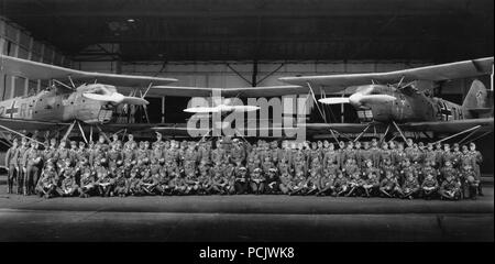 Image from the photo album of Oberleutnant Wilhelm Gaul: Kriegsmarine and Luftwaffe personnel of 1. Staffel, Küstenfliegergruppe 106 pose in front of two of the unit's Heinkel He 60 floatplanes in 1939. The aircraft now bear wartime codes and the distinctive Staffel Badge of three dice and a shaker on a black shield. The unit went to war in these aircraft before rapidly converting to the more capable Heinkel He 115. Stock Photo