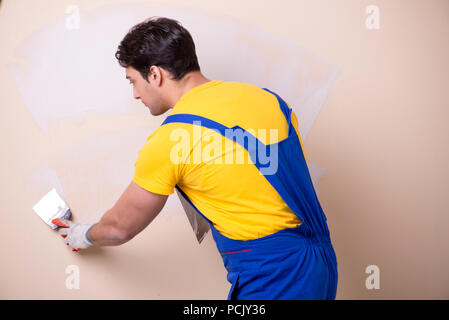 Young contractor employee applying plaster on wall Stock Photo