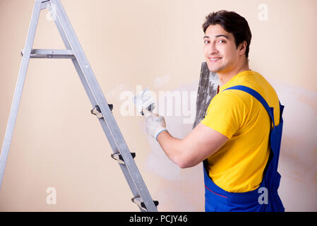 Young contractor employee applying plaster on wall Stock Photo