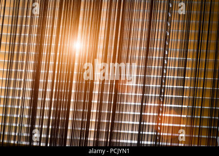 The sun shines through the closed beige horizontal blinds. Stock Photo