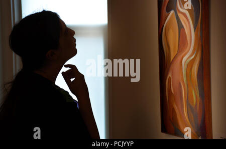 An art connoisseur emotionally studies and contemplates an abstract oil painting in an art gallery in the United States. Appearing  deep in thought. Stock Photo