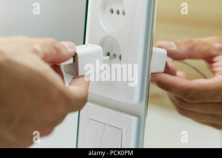Hand inserting electrical plug into outlet Stock Photo