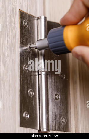 screwdriver installs door hinges Stock Photo