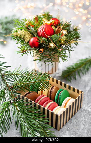 Variety of sweet macaroons in carton box. Fir branches on a gray background. Merry Christmas card. New year mood Stock Photo