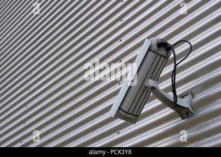 CCTV security surveillance camera attached to a corrugated iron wall. Copy space. Stock Photo