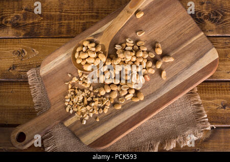 Overhead view of dry roasted peanuts on a cutting board with a rustic background Stock Photo