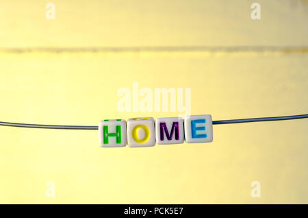 A Studio Photograph of Alphabetical Beads Suspended on a Wire Spelling 'Home' Stock Photo