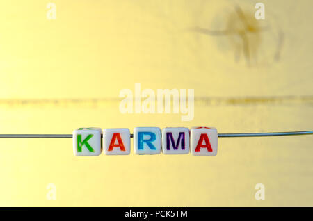 A Studio Photograph of Alphabetical Beads Suspended on a Wire Spelling 'Karma' Stock Photo