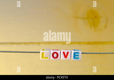 A Studio Photograph of Alphabetical Beads Suspended on a Wire Spelling 'Love' Stock Photo