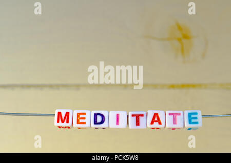 A Studio Photograph of Alphabetical Beads Suspended on a Wire Spelling 'Meditate' Stock Photo