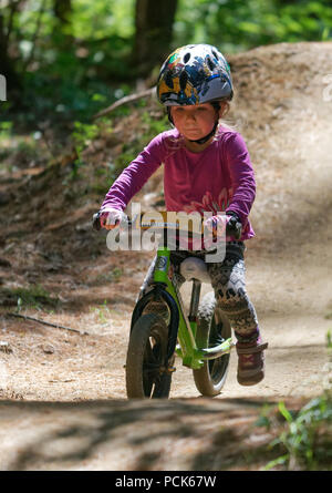 A little girl (3 yr old) riding her balance bike in the Kingdom Trails atEast Burke, Vermont, USA Stock Photo