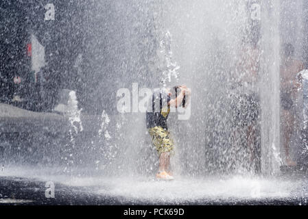 Children cooling off playing in water fountains in on Rue Jeanne Mance in Montreals Entertainment District. Taken during the 2108 heatwave. Stock Photo