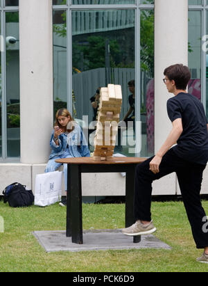 A a teenage boy playing giant Jenga, and watching his tower fall,  outside at the Jeux Loto Quebec games festival in Montreal Stock Photo