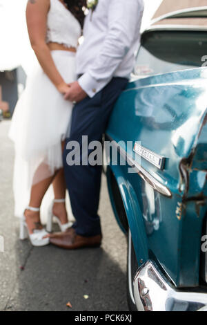 Bride and groom leaning against their wedding car Stock Photo - Alamy