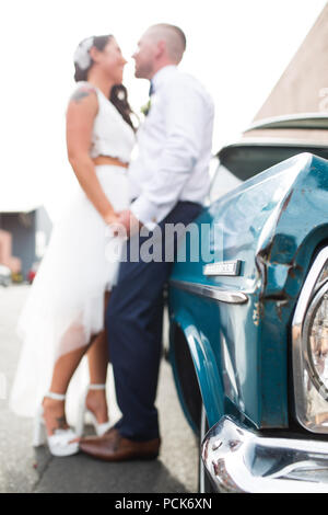 Bride and groom leaning against their wedding car Stock Photo - Alamy