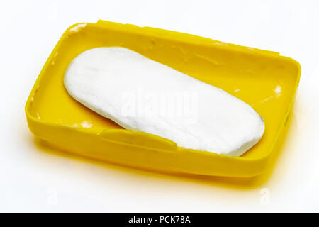 Soap residue in a yellow plastic soap dish on a white background. Stock Photo