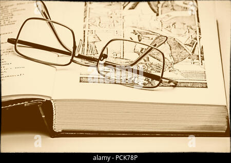 Glasses lie next to an open book. Old photo style. Stock Photo