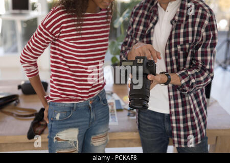 Photographer showing photos to fashion model on digital camera in studio Stock Photo