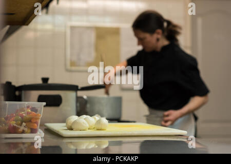 Balls of dough on a chopping board while chef cooking in background Stock Photo