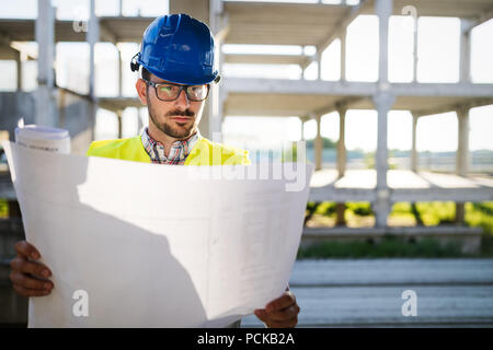 Construction engineer in hardhat with project in hands Stock Photo
