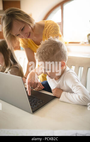 Mother teaching son using laptop at home Stock Photo
