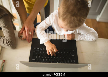 Mother teaching son using laptop at home Stock Photo