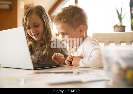 Children using laptop together in kitchen Stock Photo